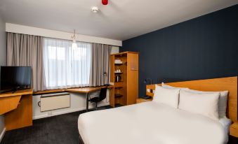 a hotel room with a bed , desk , and window , along with a red light on the ceiling at Holiday Inn Express Warwick - Stratford-Upon-Avon