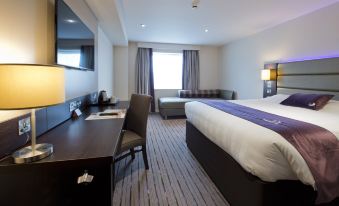 a modern hotel room with a bed , desk , and tv , along with carpeted floors and a window at Premier Inn Ulverston