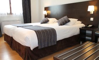 a hotel room with a double bed , a nightstand , and a lamp on the side of the bed at Logis Hotel Restaurant de l'Abbaye