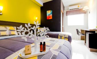 a modern hotel room with two beds , yellow walls , and black and white striped curtains at Fortune D Hotel Loei