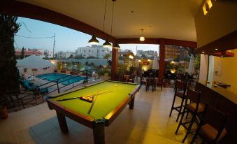 a pool table is set up in a room with chairs and tables , overlooking a pool area at Grand Hotel Madaba