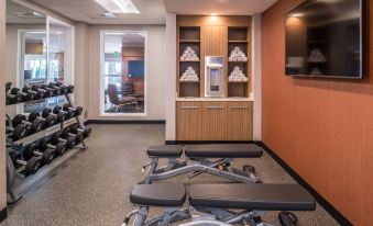 a well - equipped gym with various exercise equipment , including weight machines and a television mounted on the wall at TownePlace Suites Merced