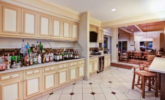 a well - equipped kitchen with various bottles of alcohol and wine displayed on the counter , along with a dining area with chairs and a table at Hilton Garden Inn Chesterton