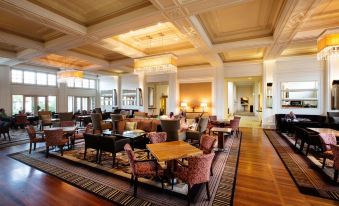 a large , well - lit hotel lobby with multiple couches and chairs arranged around a dining table at Hyatt Hotel Canberra - A Park Hyatt Hotel