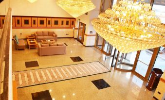 a large hotel lobby with a marble floor , multiple couches , and a chandelier hanging from the ceiling at Nooh Tower