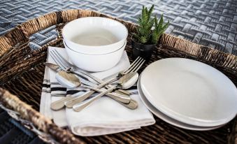 a dining table set with a variety of dishes , including bowls , forks , knives , and spoons at Wild Arrow Ranch