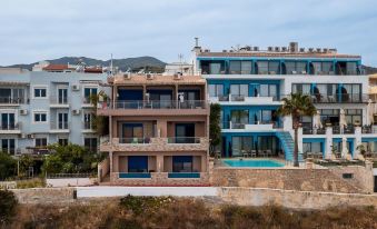 a row of houses with a swimming pool in the front and palm trees in the background at Minos Boutique Hotel