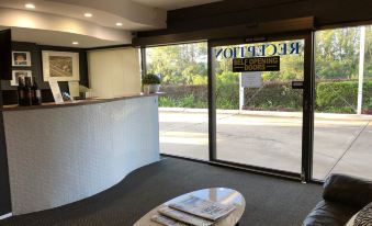 a modern office interior with a reception area , couches , and a table , as well as large windows that offer views of the outside at Logan City Motor Inn