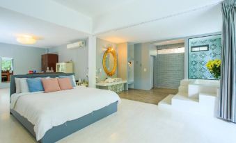 a modern bedroom with white walls , a blue bed , and a large mirror on the wall at Villa Moreeda