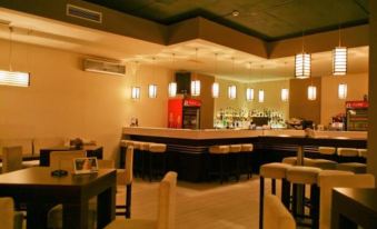 a modern bar with white walls , wooden floors , and multiple seating options , including chairs and tables at Hotel Bulgaria