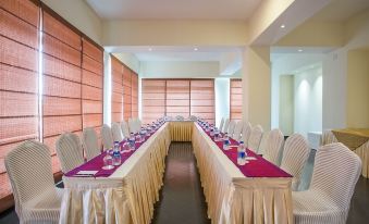 a long dining table with white chairs and purple tablecloths , set up for a formal event at Hotel Grand Park Barishal