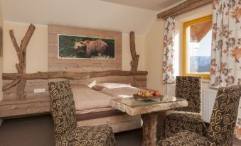 a cozy bedroom with a wooden bed , two chairs , and a window , decorated with a painting of a bear on the wall at Hohenstein