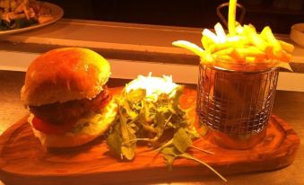 a wooden dining table with a plate of food , including a burger , french fries , and salad at The Village Inn