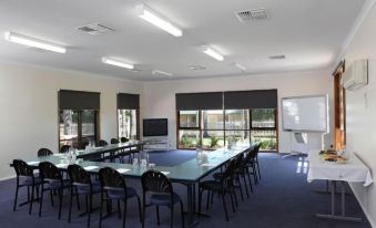a conference room with a long table and chairs , a whiteboard , and large windows on the right side at Murray Downs Resort