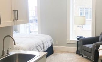 a clean , modern bedroom with white walls , gray carpet , and a bed near a window at Inn on Central