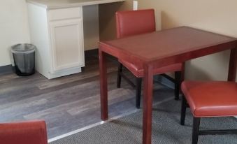 a red wooden table with two chairs in a room with white cabinets and gray flooring at Wine Valley Inn