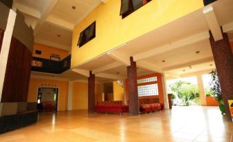 a large , open room with a red couch and wooden columns is shown in this image at Hotel Selopanggung Kediri