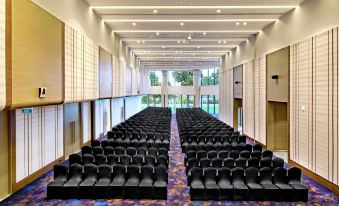 a large conference room with rows of black chairs arranged in a semicircle , providing seating for a large group of people at DoubleTree by Hilton Ahmedabad