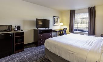 a hotel room with a bed , desk , and television , along with curtains and a window at Cobblestone Inn & Suites - Brookville