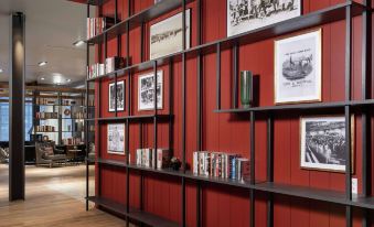 a bookshelf filled with books and framed photos is mounted on a red wall in a room at Canopy by Hilton Ithaca Downtown