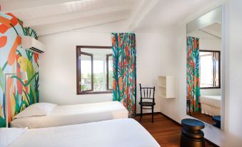 a modern hotel room with white walls , wooden floors , and large windows decorated with colorful curtains at Papagayo Beach Resort