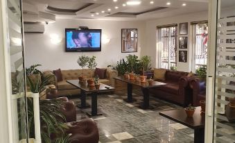 a living room with brown leather couches and chairs arranged around a tv , creating a cozy atmosphere at Green Hill Hotel