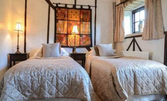 a bedroom with two beds , each covered in white linens and a decorative window above them at Thames Head Inn