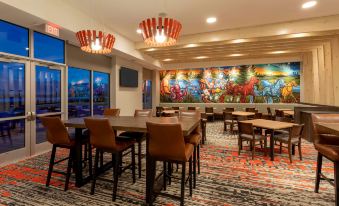 a restaurant with wooden tables and chairs , a colorful mural on the wall , and a window at Running Aces Hotel & Casino Trademark Collection by Wyndham