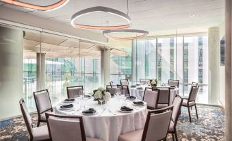 a formal dining room with multiple round tables , chairs , and a chandelier hanging from the ceiling at Civic Hotel, Autograph Collection