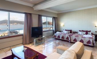 a living room with a couch , chairs , and a tv . the room has a view of the water at Hotel Bahía de Vigo