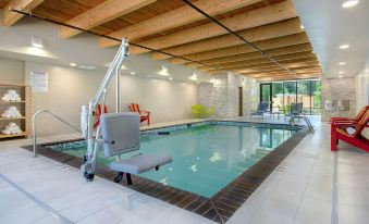 a large indoor swimming pool surrounded by a wooden deck , with lounge chairs and umbrellas placed around it at Home2 Suites by Hilton Marysville