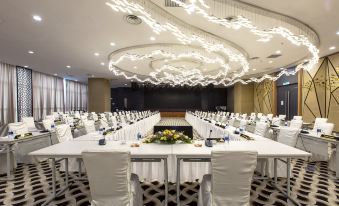 a large conference room with rows of tables and chairs , white tablecloths , and decorative lights hanging from the ceiling at Fraser Place Puteri Harbour, Johor