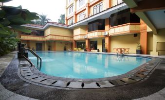 a large swimming pool surrounded by a building , with several people enjoying their time in the pool at Sari Ater Kamboti Hotel Bandung
