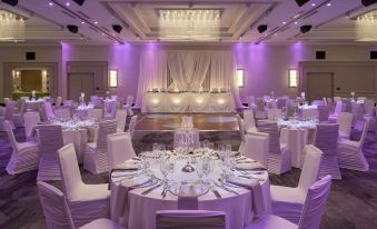 a large banquet hall with multiple round tables covered in white tablecloths and set for a formal event at Courtyard Oshawa