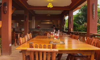 a wooden dining table with chairs and a fire pit in the background , surrounded by a room filled with chairs at Victoria Guest House