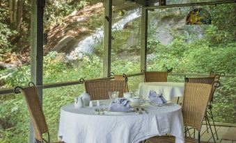 a dining table set with white tablecloths , silverware , and wine glasses in a restaurant setting at Sylvan Falls Mill B&B