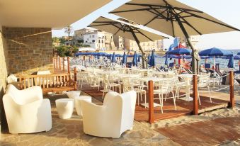 a restaurant with white tables and chairs , blue umbrellas , and a view of the ocean at Hotel la Playa