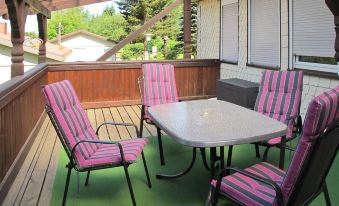 a wooden deck with a table and chairs on it , surrounded by trees and a fence at Aurora