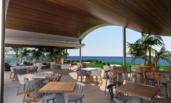 an outdoor dining area at a restaurant , with tables and chairs arranged for guests to enjoy the view of the ocean at Radisson Beach Resort Larnaca