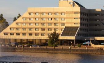 a large hotel building with multiple floors , situated next to a body of water in a city setting at Druzhba