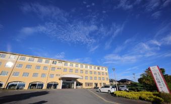 a large , modern building with a parking lot in front of it under a blue sky at Fuji Matsuzono Hotel