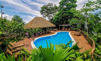 a large outdoor swimming pool surrounded by lush greenery , with several lounge chairs placed around the pool at Lapa Rios Lodge by Boena
