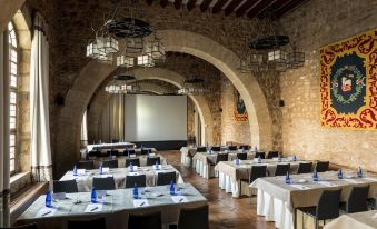 a large dining room with multiple tables and chairs set up for a formal event , possibly a wedding reception at Parador de Siguenza