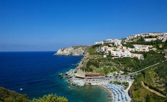 a picturesque coastal town with a beach and ocean in the background , under a clear blue sky at Athina Palace Resort & Spa