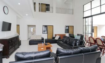 a spacious living room with black leather couches and chairs , creating a warm and inviting atmosphere at Adel Guest House