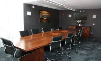 a conference room with a long wooden table , black chairs , and a large painting on the wall at Delta Hotels by Marriott Milwaukee Northwest