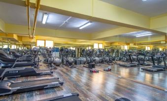 a large , well - equipped gym with various exercise equipment and a few people working out on treadmills at Prime Inn