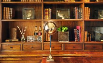 a bookshelf filled with books , a bottle of wine , and various decorative items such as a globe and a vase at Rosewood Castiglion del Bosco