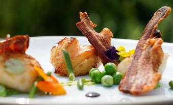 a white plate with a variety of food items , including grilled salmon , asparagus , and peas at The Fishbourne