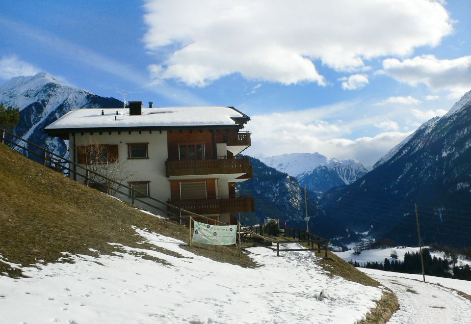 a large house with a balcony is situated on a snow - covered hillside overlooking mountains at Eva